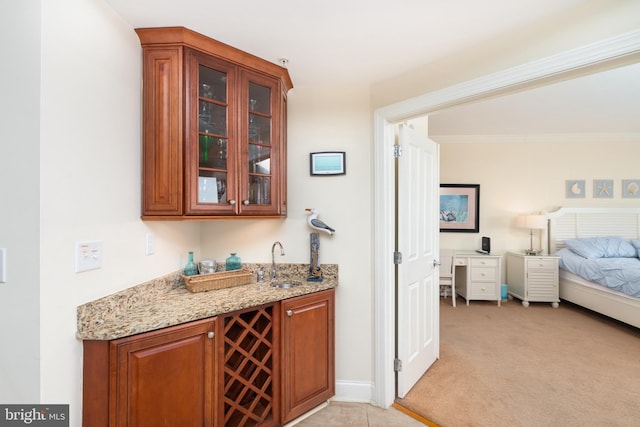 bar featuring light stone counters, sink, and light carpet