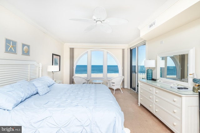 bedroom with multiple windows, light carpet, ornamental molding, and a water view