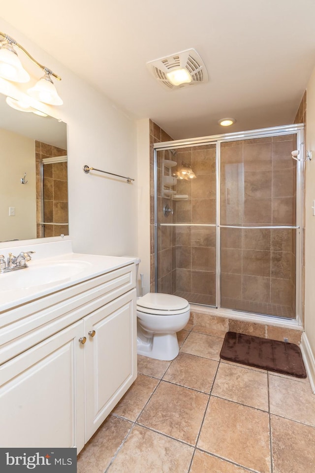 bathroom with tile patterned flooring, vanity, a shower with shower door, and toilet