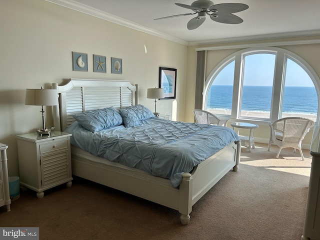 bedroom with a beach view, a water view, crown molding, dark carpet, and ceiling fan