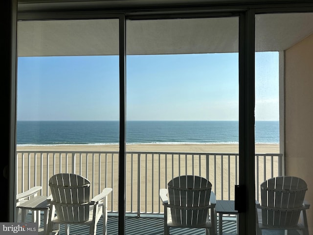 unfurnished sunroom with a water view and a view of the beach