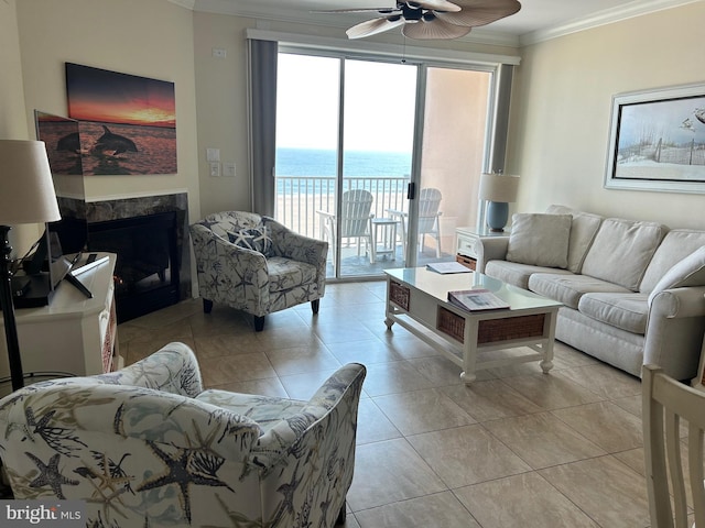 living room featuring a water view, crown molding, light tile patterned floors, ceiling fan, and a high end fireplace