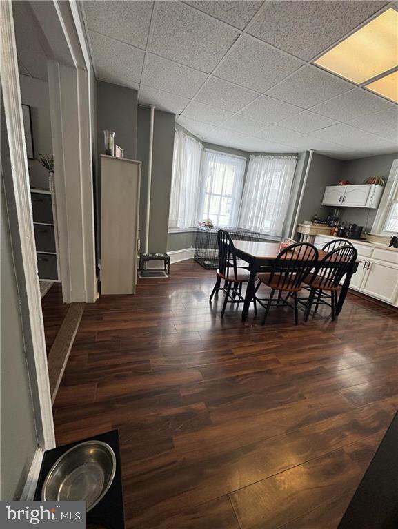 dining space featuring a paneled ceiling and dark hardwood / wood-style flooring