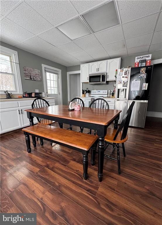 dining area with dark wood-type flooring and a paneled ceiling