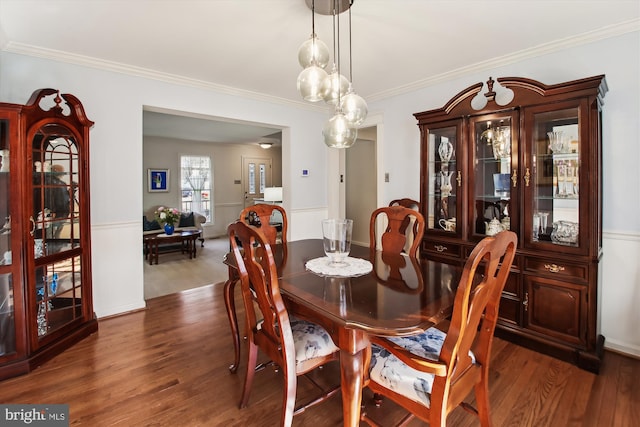 dining space with dark hardwood / wood-style flooring and crown molding