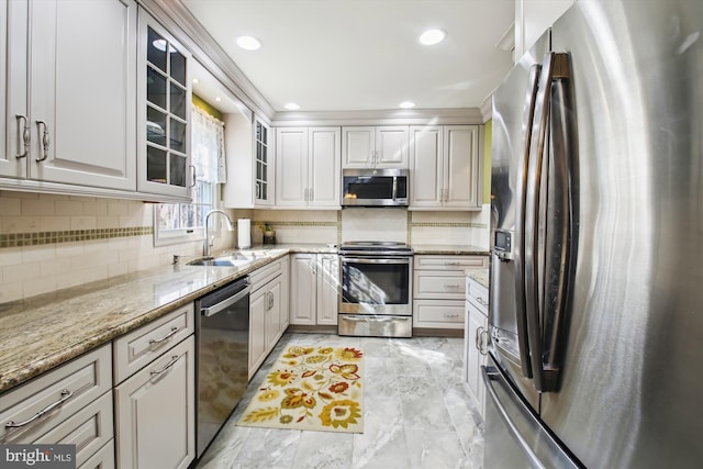 kitchen featuring sink, appliances with stainless steel finishes, white cabinetry, tasteful backsplash, and light stone countertops