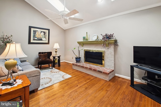 living room featuring lofted ceiling, hardwood / wood-style flooring, ceiling fan, crown molding, and a brick fireplace