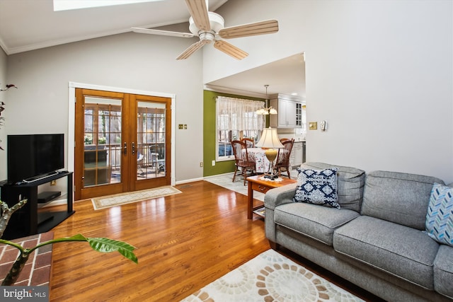 living room featuring hardwood / wood-style floors, lofted ceiling, ceiling fan, crown molding, and french doors