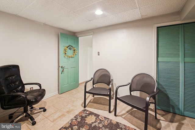 sitting room featuring a paneled ceiling and light tile patterned flooring