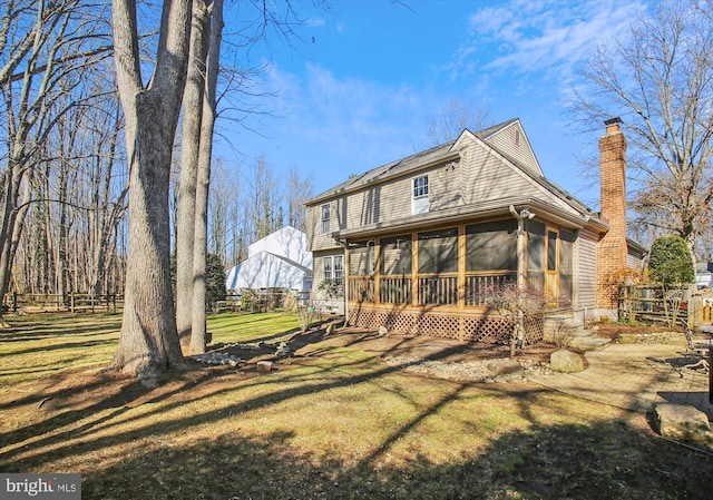 rear view of house with a lawn and a sunroom