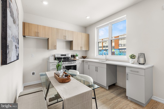 kitchen with sink, light brown cabinets, electric range, and light hardwood / wood-style floors