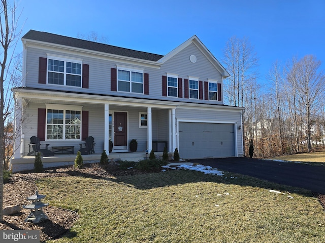 view of property featuring a garage, covered porch, and a front yard