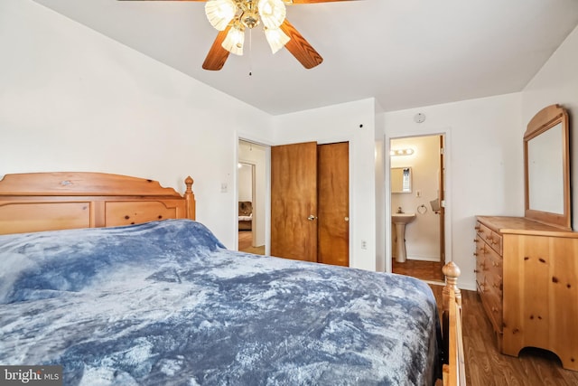 bedroom with hardwood / wood-style flooring, ceiling fan, connected bathroom, and sink