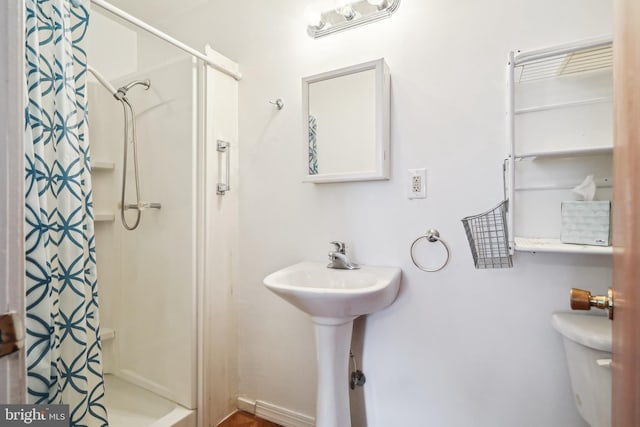 bathroom with toilet, sink, and walk in shower