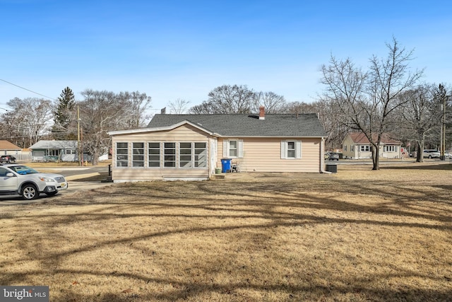 back of property with a sunroom and a lawn