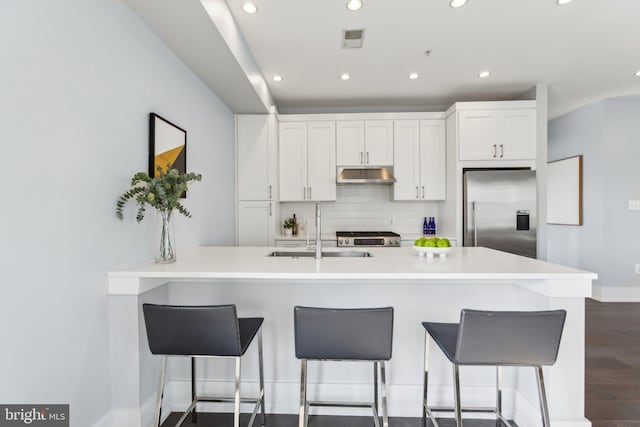 kitchen with white cabinetry, a breakfast bar area, stainless steel built in fridge, and sink