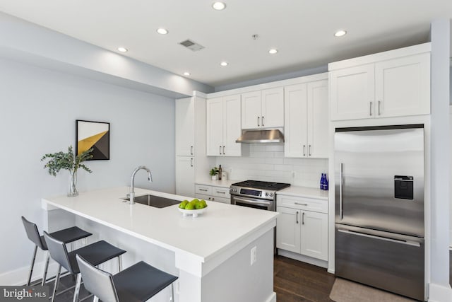 kitchen featuring sink, appliances with stainless steel finishes, backsplash, dark hardwood / wood-style floors, and white cabinets