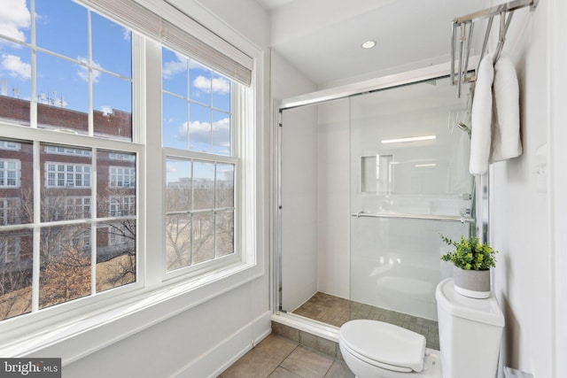 bathroom featuring toilet, tile patterned flooring, and a shower with door