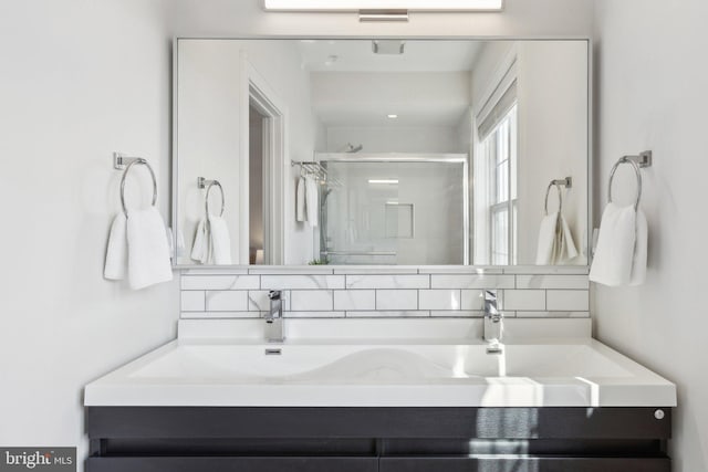 bathroom featuring vanity, tasteful backsplash, and a shower with door