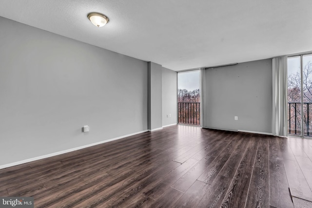 empty room featuring dark hardwood / wood-style flooring, plenty of natural light, expansive windows, and a textured ceiling