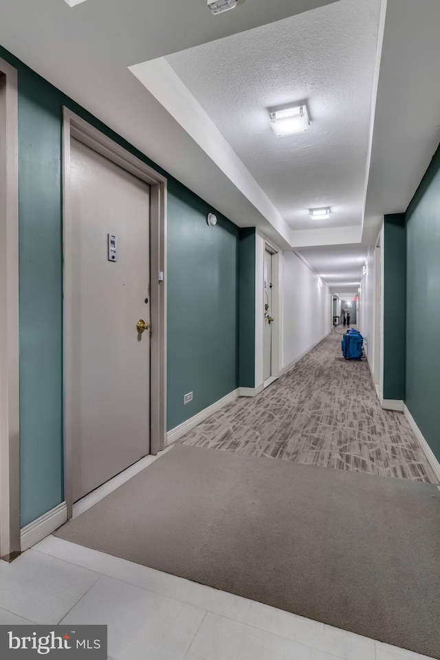 hall with carpet floors and a textured ceiling