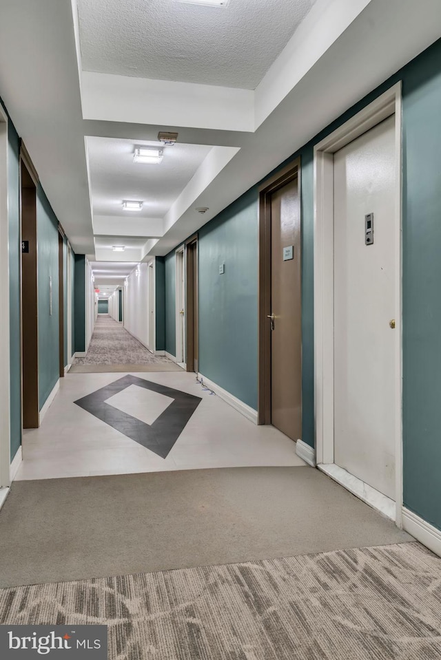 hall featuring light colored carpet and a textured ceiling