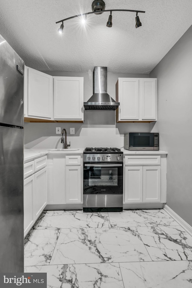 kitchen with wall chimney exhaust hood, stainless steel appliances, sink, and white cabinets