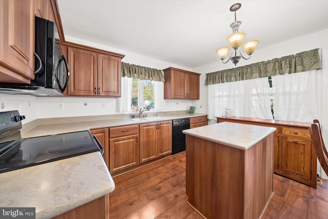 kitchen with sink, hanging light fixtures, dark hardwood / wood-style floors, a center island, and black appliances