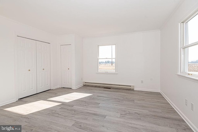 unfurnished bedroom featuring crown molding, baseboard heating, and light hardwood / wood-style floors