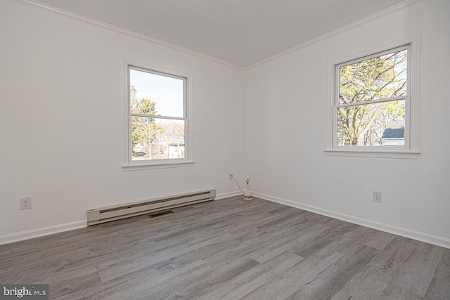 spare room with crown molding, a baseboard heating unit, light hardwood / wood-style floors, and a healthy amount of sunlight