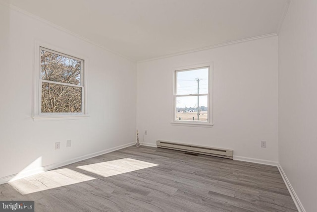 spare room with crown molding, hardwood / wood-style flooring, and baseboard heating