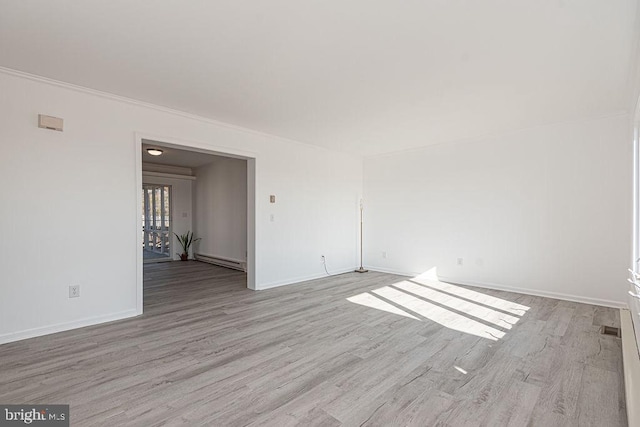 spare room featuring a baseboard heating unit and light hardwood / wood-style flooring