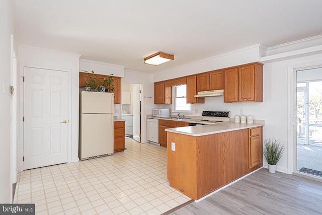 kitchen with washer / clothes dryer, sink, kitchen peninsula, crown molding, and white appliances