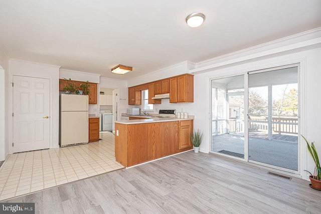 kitchen featuring white appliances, a wealth of natural light, washer / dryer, and kitchen peninsula