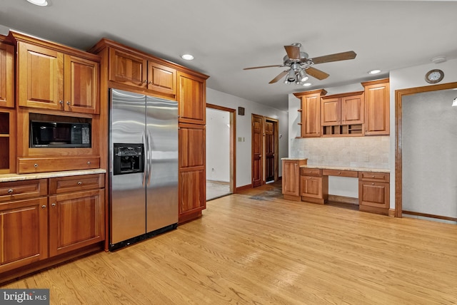 kitchen featuring built in desk, tasteful backsplash, black microwave, stainless steel refrigerator with ice dispenser, and light wood-type flooring