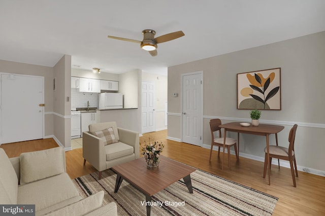 living room with ceiling fan, sink, and light wood-type flooring