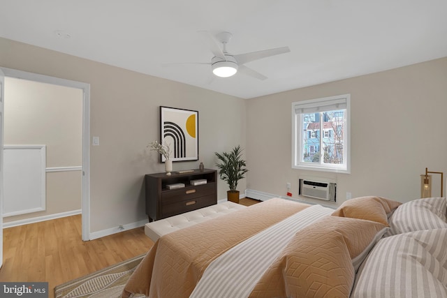 bedroom with ceiling fan, light hardwood / wood-style floors, and a wall mounted AC