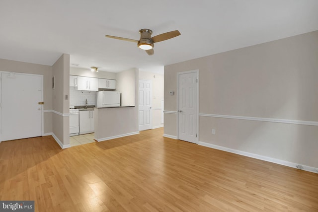 unfurnished living room featuring ceiling fan, sink, and light hardwood / wood-style flooring