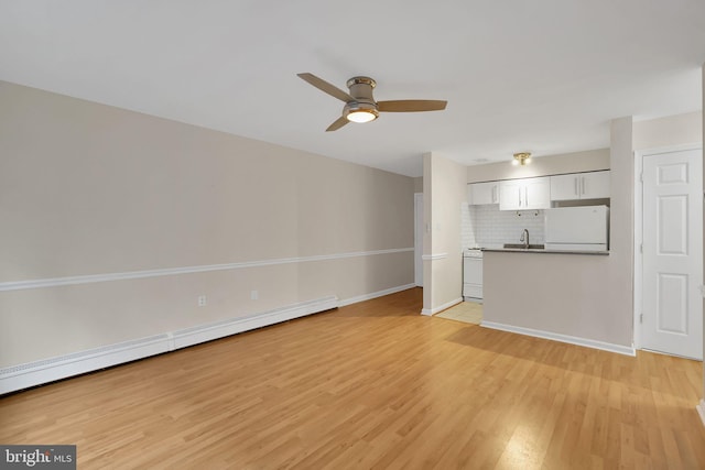 unfurnished living room with sink, light wood-type flooring, ceiling fan, and baseboard heating