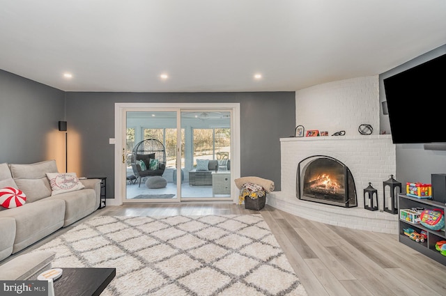 living room featuring a brick fireplace and light hardwood / wood-style flooring