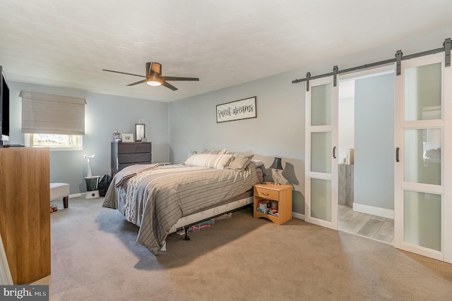 bedroom with light carpet, a barn door, and ceiling fan