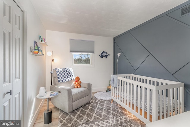 bedroom featuring a nursery area and hardwood / wood-style floors