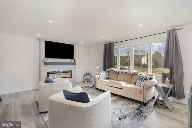 living room with light hardwood / wood-style flooring and a large fireplace