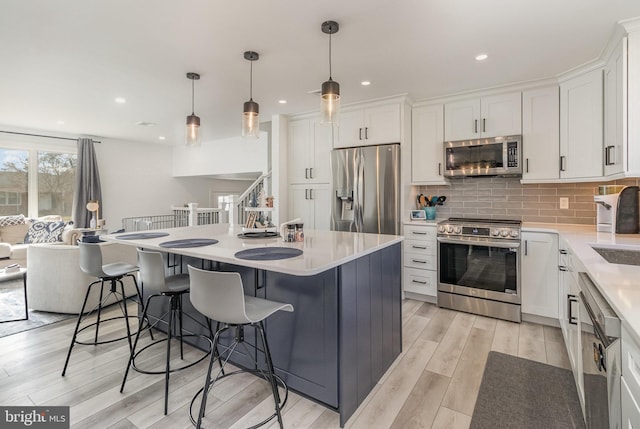 kitchen with decorative light fixtures, white cabinets, and appliances with stainless steel finishes