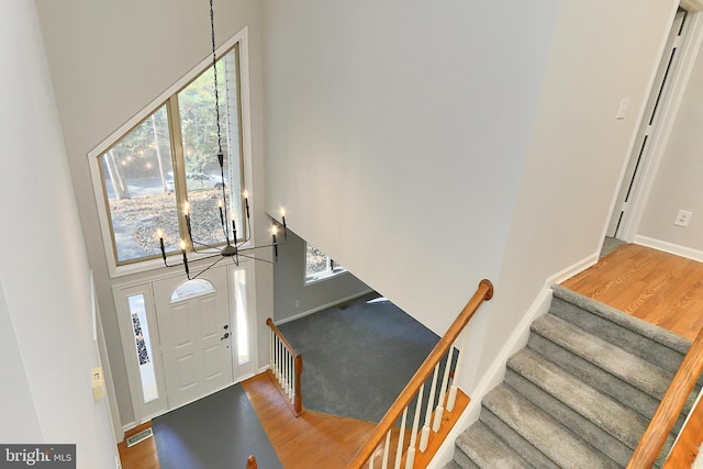 entryway featuring hardwood / wood-style flooring, a chandelier, and a high ceiling