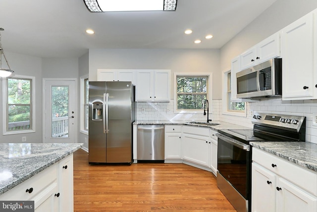 kitchen featuring hanging light fixtures, white cabinetry, appliances with stainless steel finishes, and sink