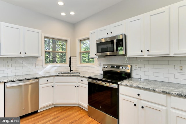 kitchen with light stone countertops, white cabinetry, appliances with stainless steel finishes, and sink