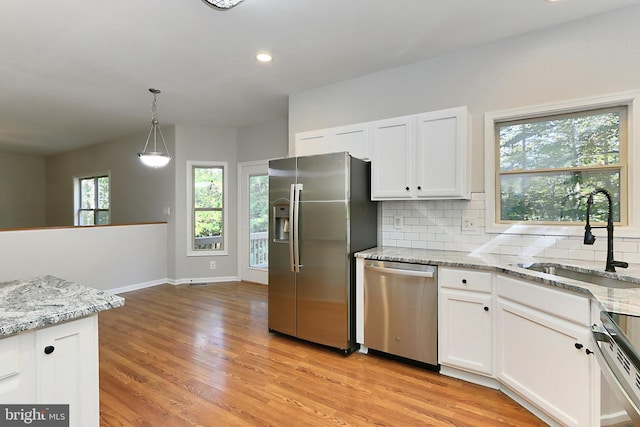 kitchen with white cabinetry, sink, light stone countertops, and appliances with stainless steel finishes