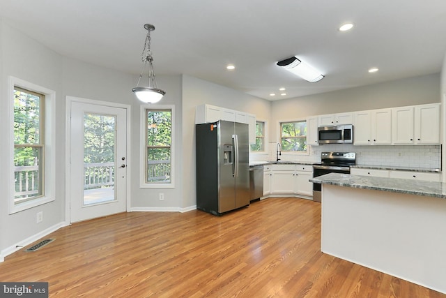 kitchen featuring pendant lighting, sink, appliances with stainless steel finishes, light stone countertops, and white cabinets