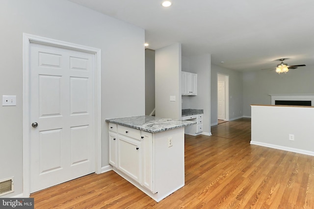 kitchen featuring white cabinetry, kitchen peninsula, ceiling fan, light stone countertops, and light hardwood / wood-style floors